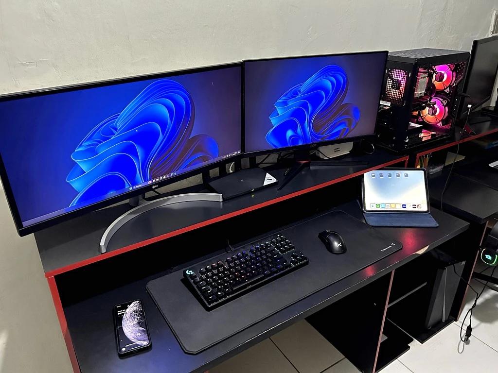 Foto do meu ambiente de trabalho, minha mesa, meus monitores e computador assim como os periféricos que eu uso no dia a dia.